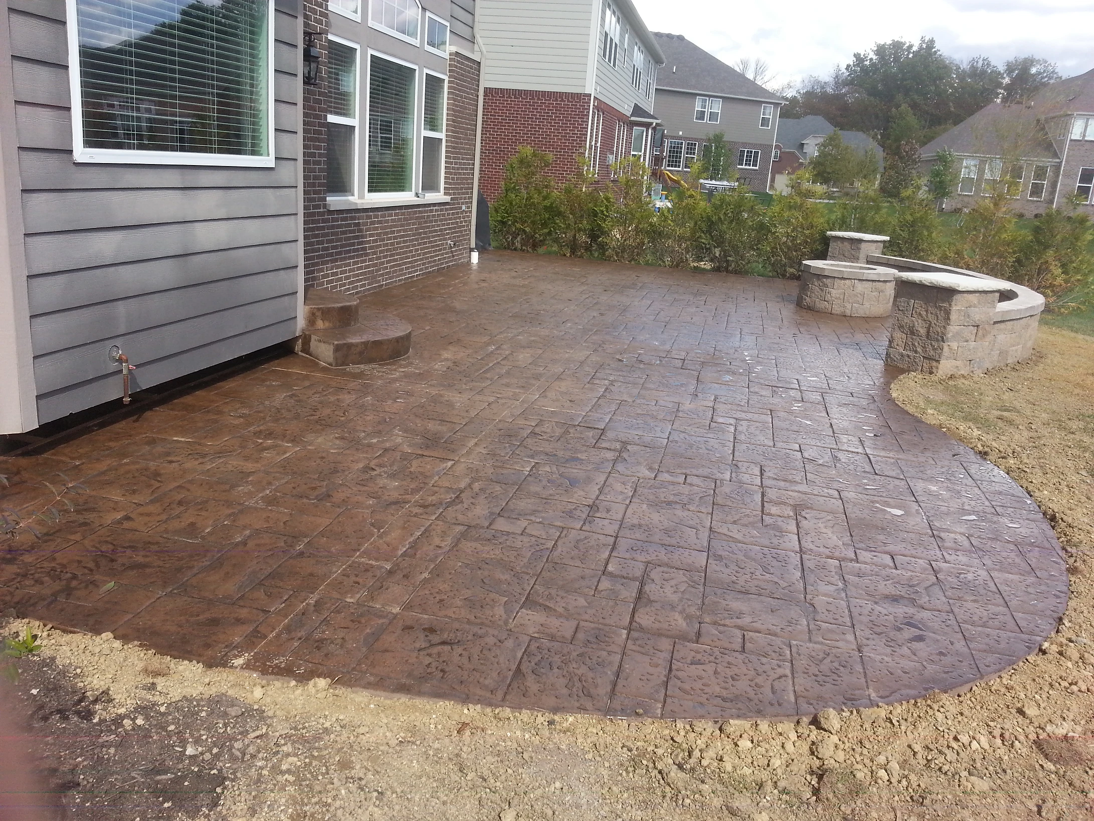 Stamped concrete patio with curved edge and stone fire pit