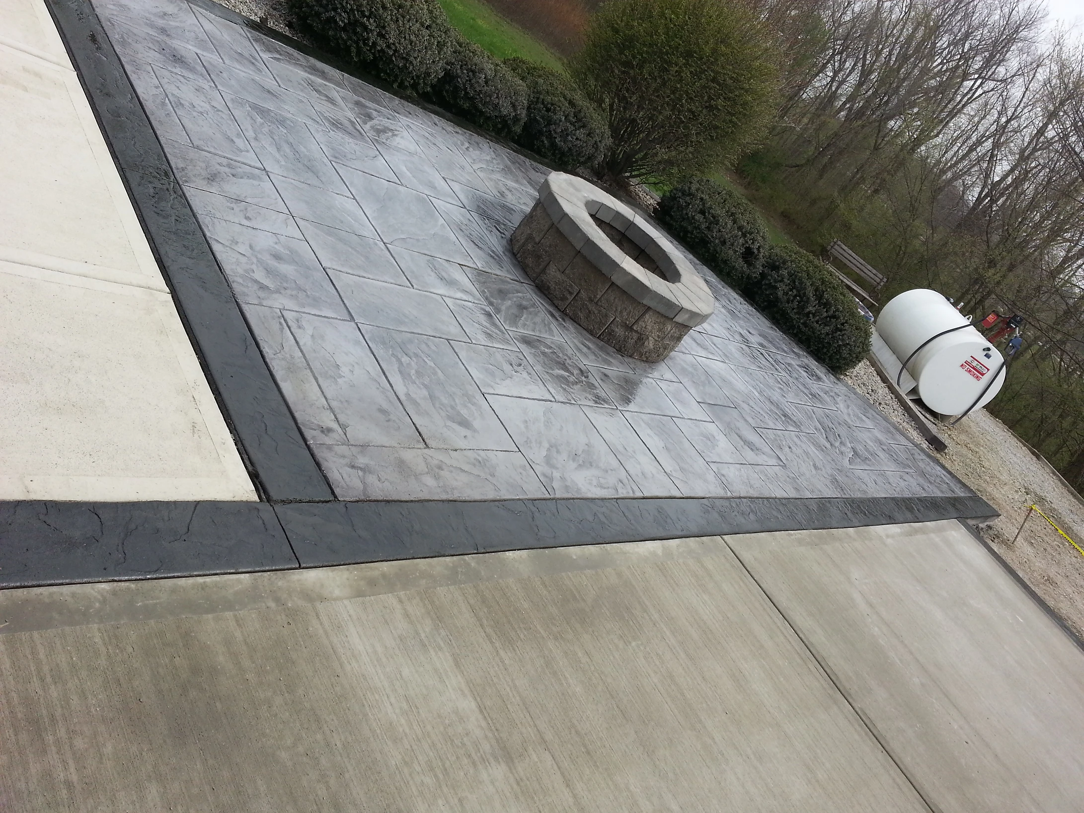 Stamped concrete patio with stone fire pit and propane tank