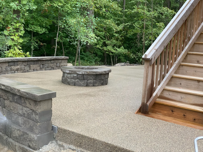 Stone patio with fire pit, wooden stairs, and lush green forest backdrop