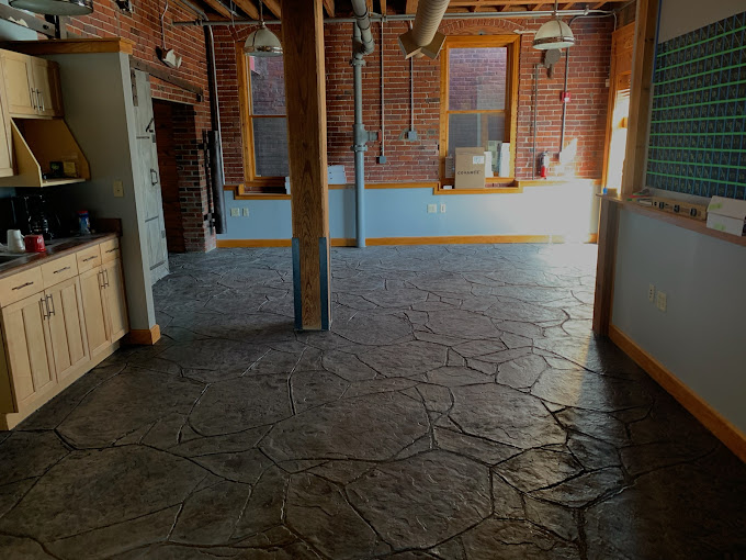 Industrial kitchen with stone floor, exposed brick walls, and wooden cabinets
